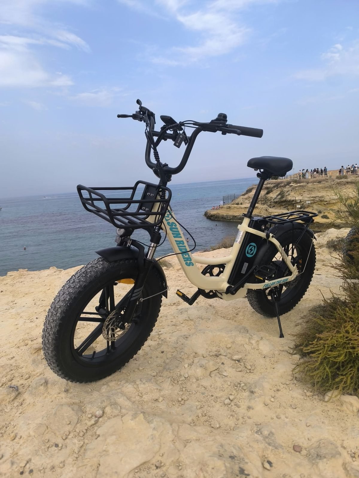 Bicicleta eléctrica urbana de alquiler con ruedas anchas sobre las rocas junto al mar, El Campello