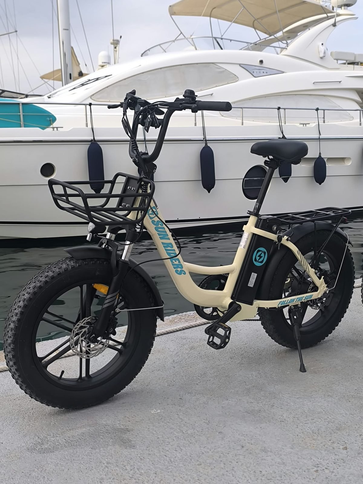 Dos bicicletas eléctricas de alquiler junto a un yate en el puerto de El Campello